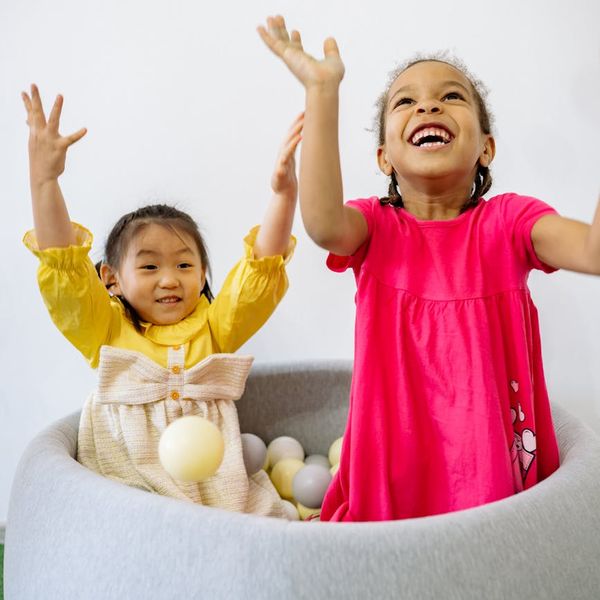 Group of diverse children laughing and playing together in a bright room.